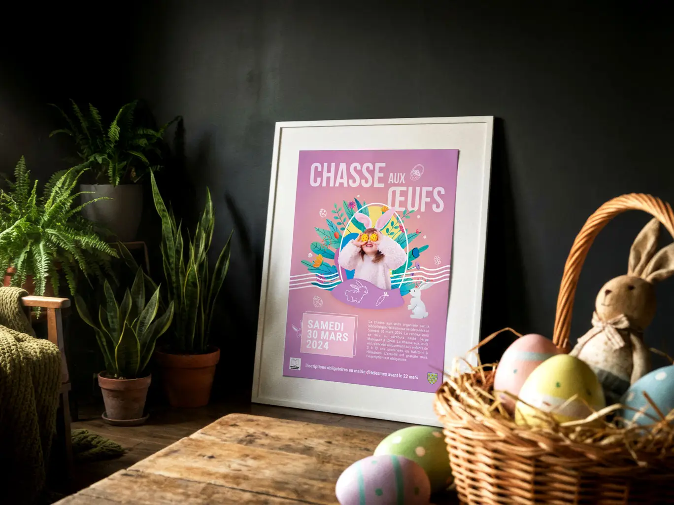 Affiche de pâques de la commune d'Hélesmes sur une table en bois avec un panier d'oeuf de pâques